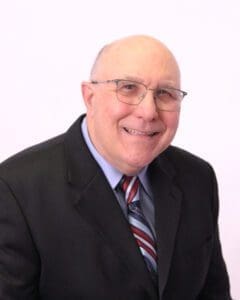 Smiling elderly man in a suit and tie.