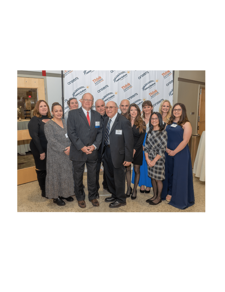 Group of people posing at a formal event with a branded backdrop.