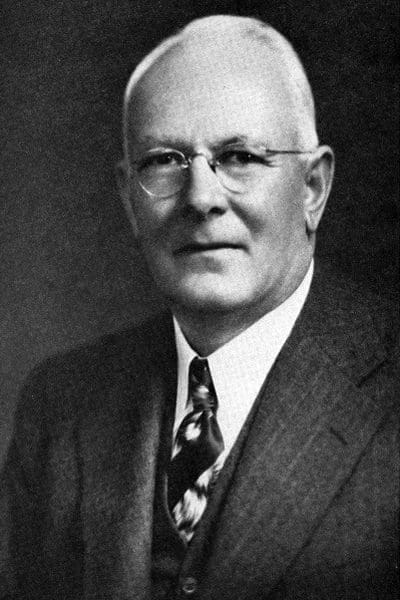 Black and white portrait of an elderly man in a suit and tie.