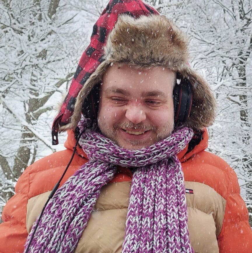 Two people dressed warmly enjoying a snowy day in a forest.
