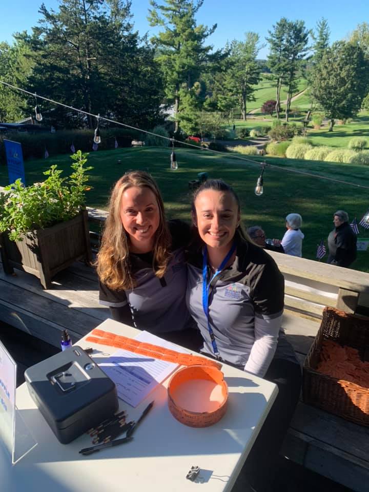 Two women sitting outdoors at a table on a sunny day.