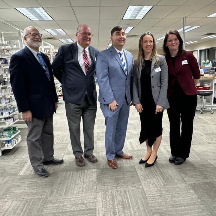 Five professionals posing together in an office setting.