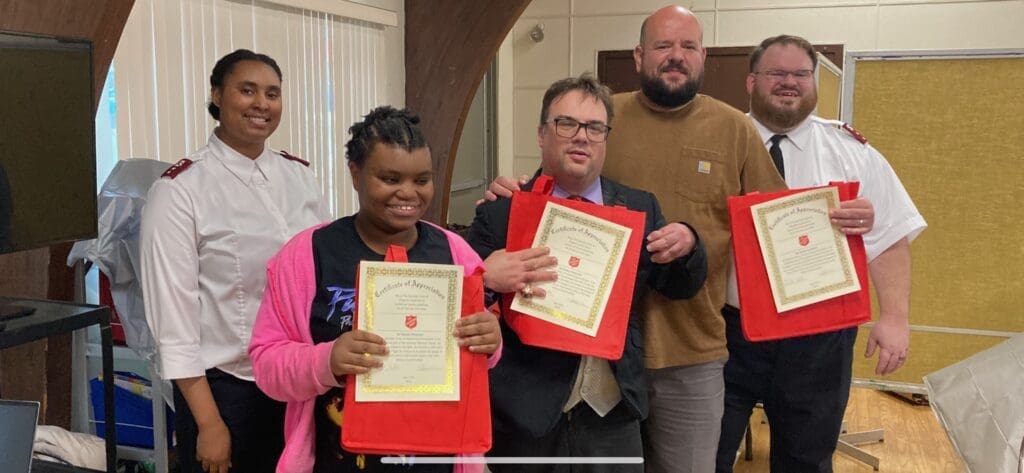 Two people proudly holding certificates, posing with a third person.