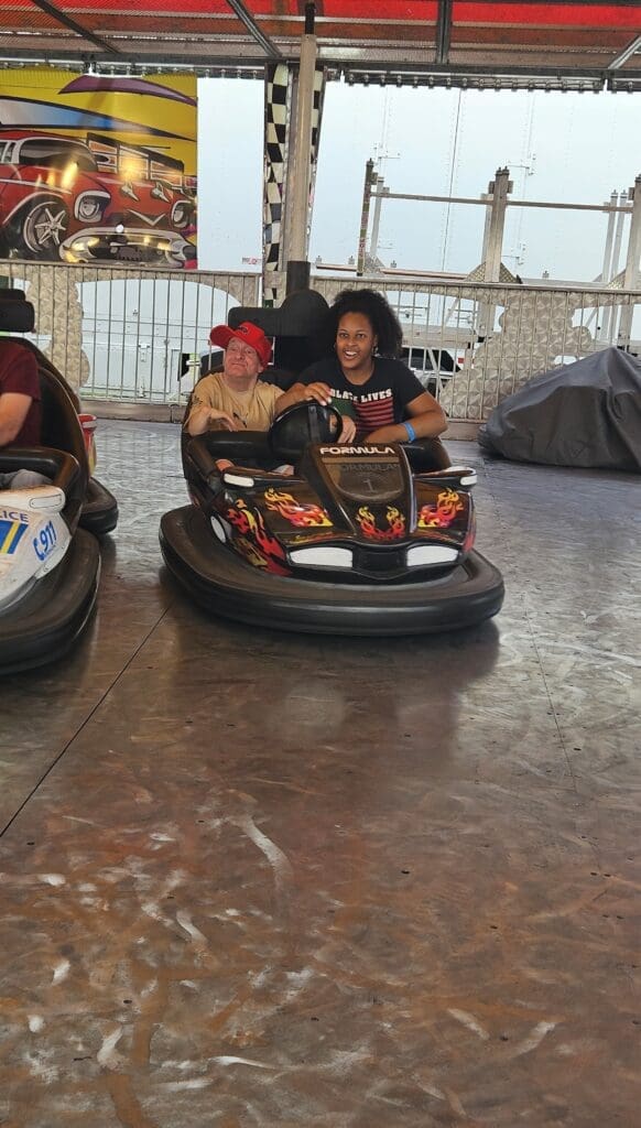 Two people enjoying a ride in bumper cars indoors.
