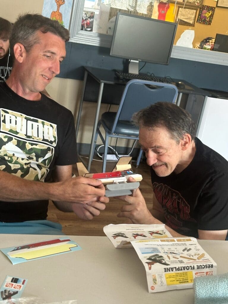 Two men sharing a laugh while looking at a handheld device.
