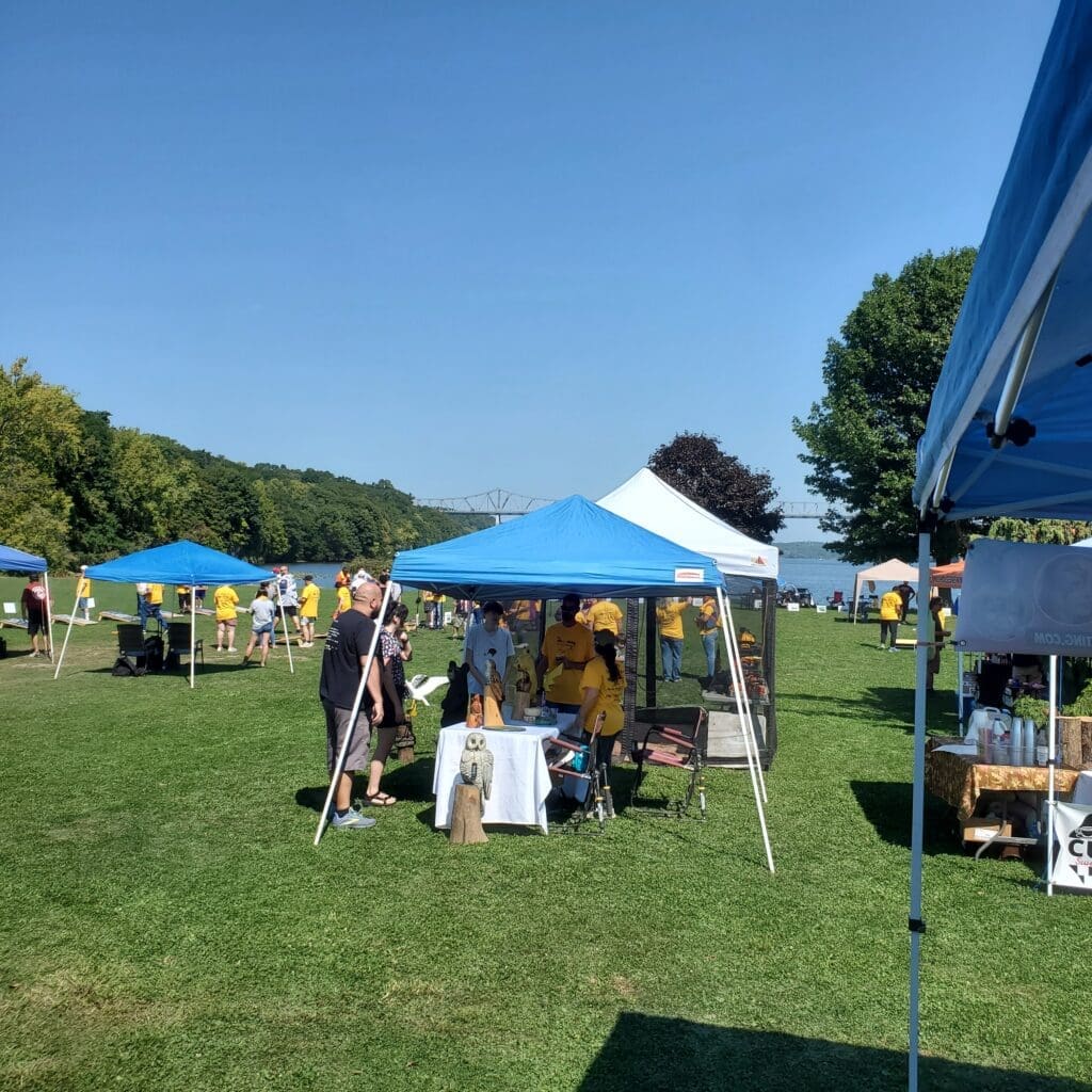 Outdoor market scene with vendors under blue tents on a sunny day.
