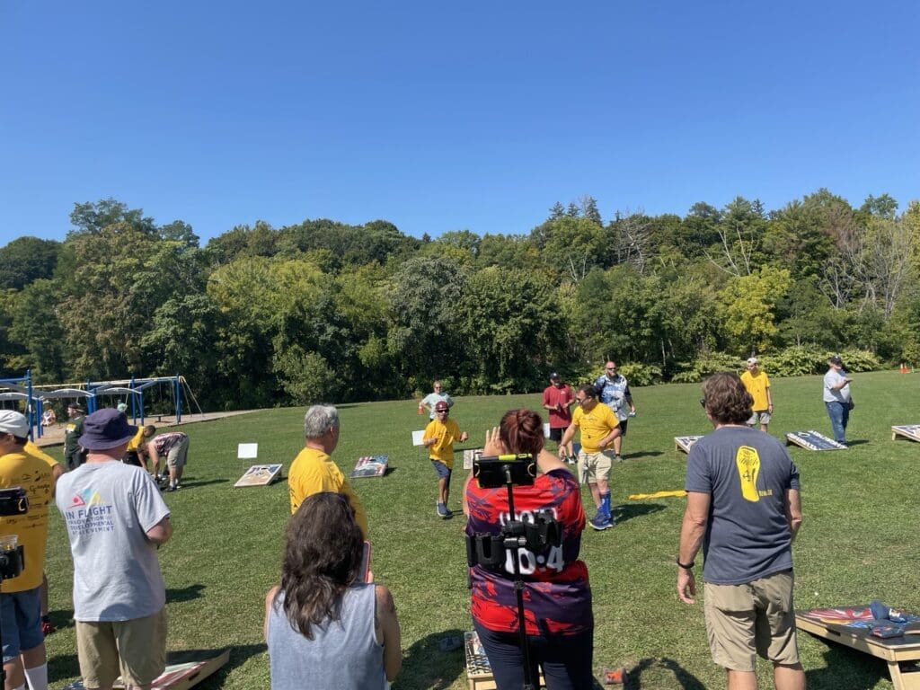People watching and capturing a soccer game on a sunny day.