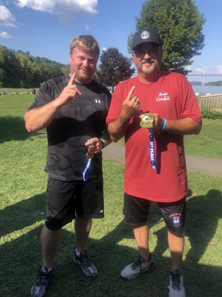 Two men posing outdoors in casual summer attire.