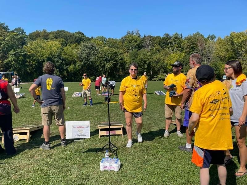 Group of people in yellow shirts playing an outdoor game on a sunny day.