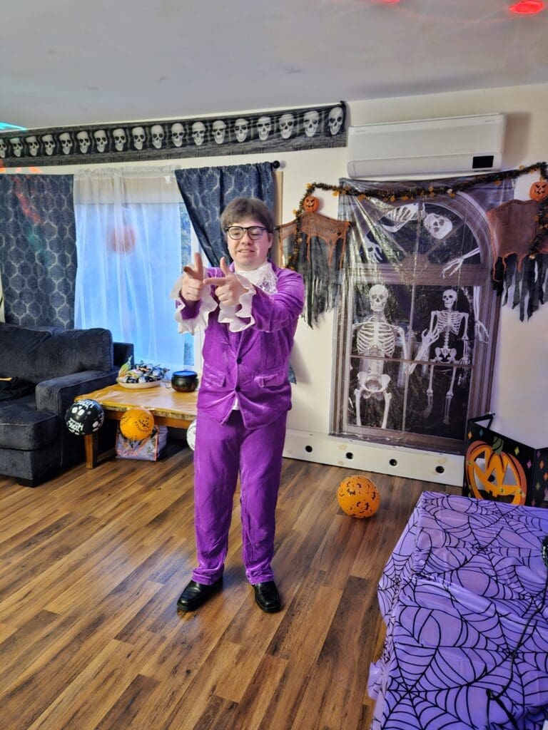 Person in a purple suit performing a dramatic gesture indoors.