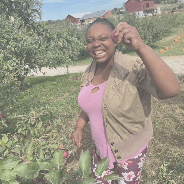 A smiling woman harvesting vegetables in a garden on a sunny day.