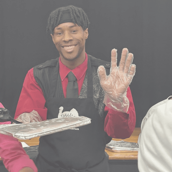 A smiling waiter making an OK hand gesture holding a tray.
