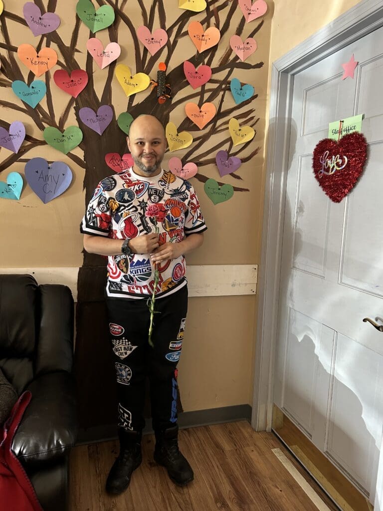 Woman holding a magazine, standing next to a colorful heart-shaped paper display.