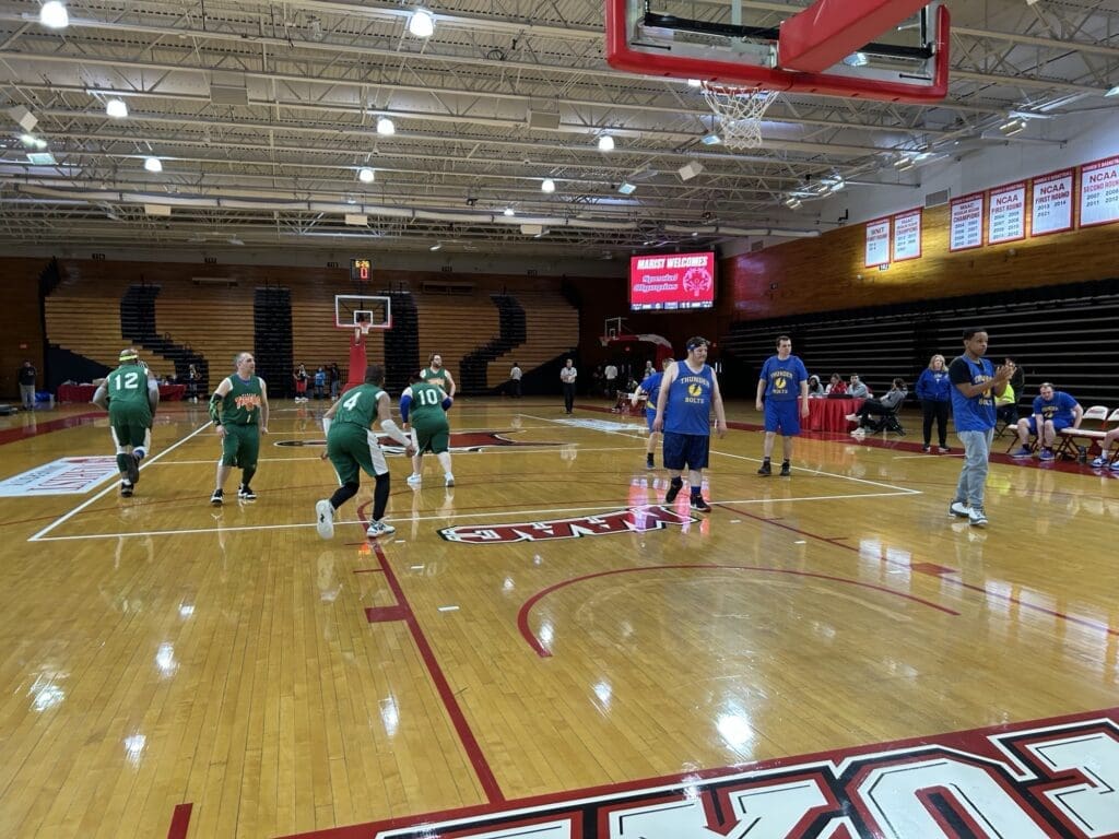 Children playing basketball in a gymnasium during a game.