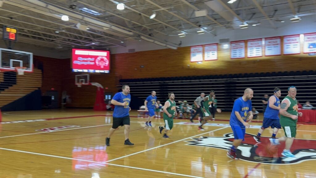 Youth basketball game in a gymnasium with players running on the court.