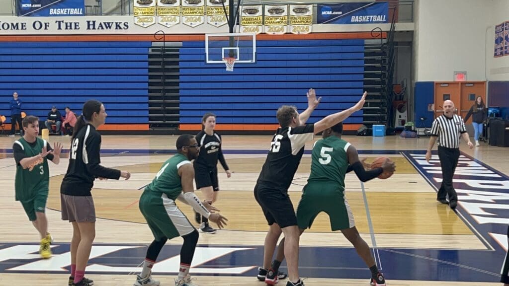 High school girls basketball game with players defending near the basket.