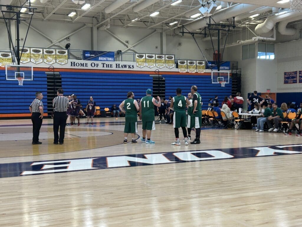 Young basketball players in green uniforms warming up on a gym court.