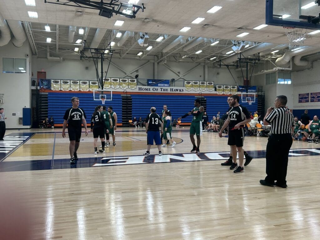 High school basketball game in progress with players warming up.