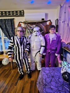 Three people in Halloween costumes posing indoors.