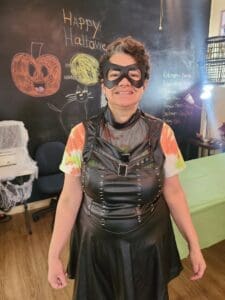 Person in a black leather outfit and cat mask at a Halloween party.