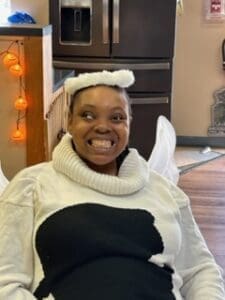 Smiling woman wearing a cozy white sweater and headband indoors.