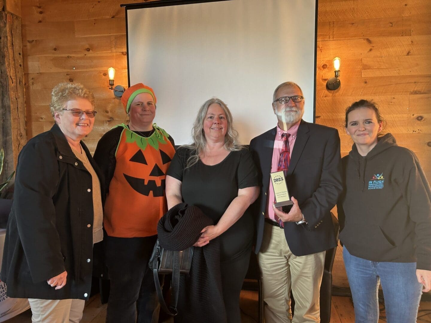 Group of five people posing indoors with festive Halloween attire.