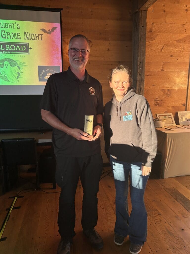 Two people standing indoors holding an award or trophy.