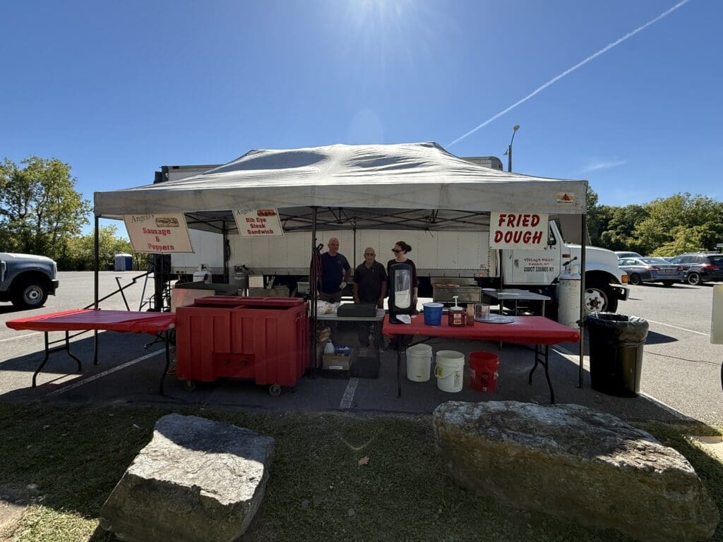 Outdoor taco truck with people serving food on a sunny day.