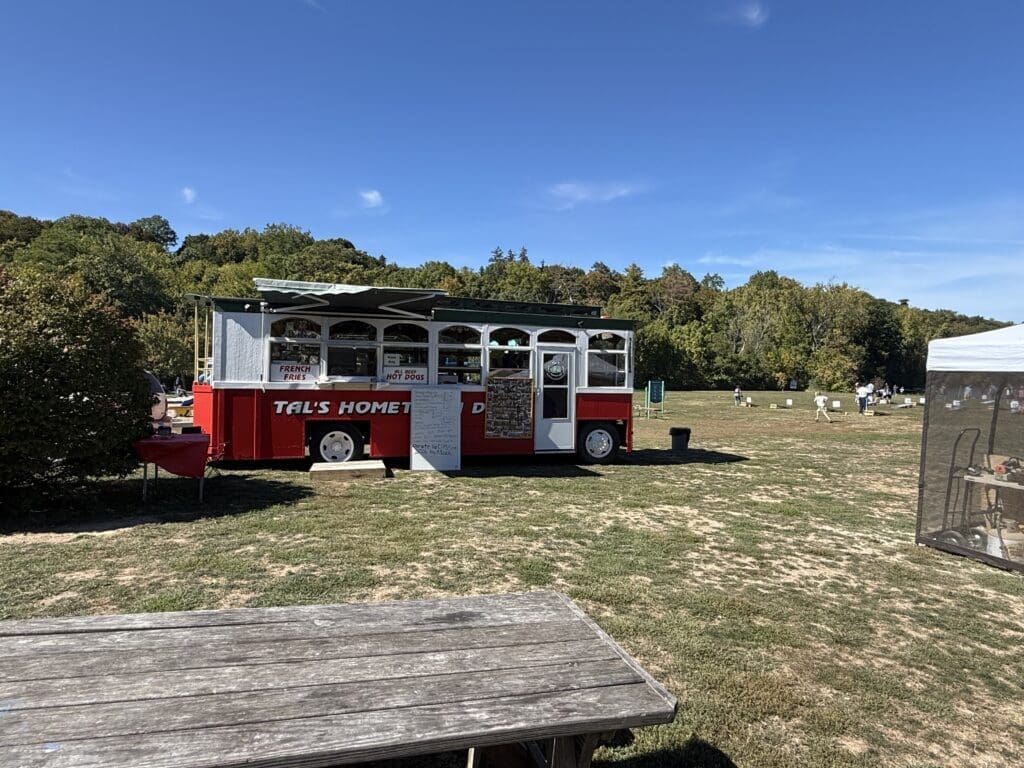 A red and white train car parked on grass under a clear blue sky.