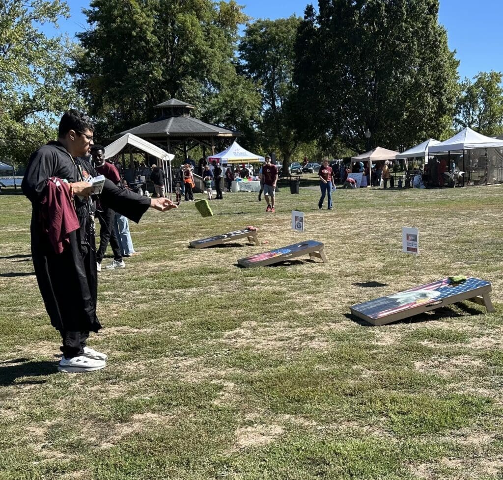 People playing cornhole outdoors on a sunny day.
