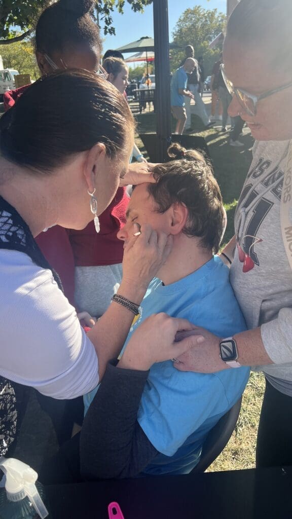 Woman gently touching a young boy's face outdoors.