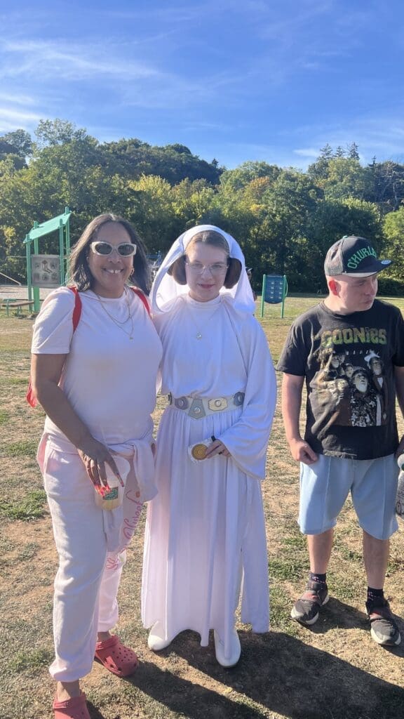 Three people posing outdoors, including a girl dressed as Princess Leia.
