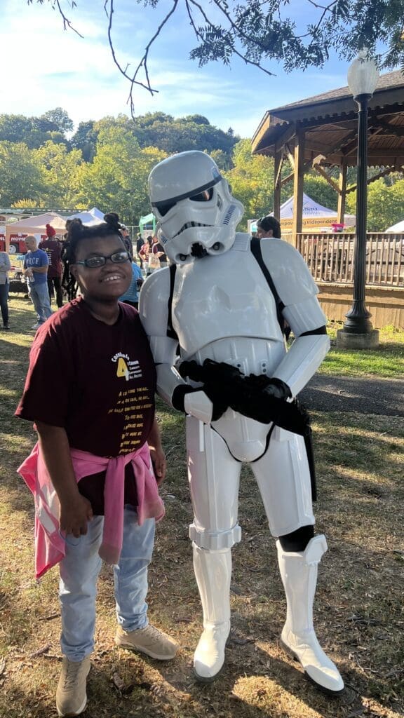 Person in Star Wars Stormtrooper costume posing with a smiling woman outdoors.