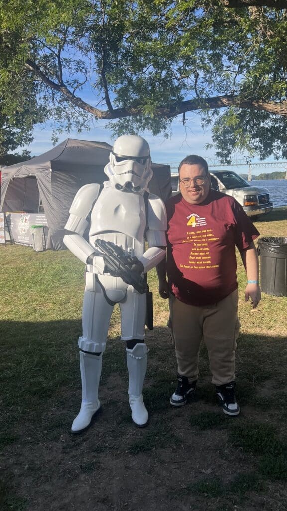 A person posing with a Stormtrooper in a park on a sunny day.