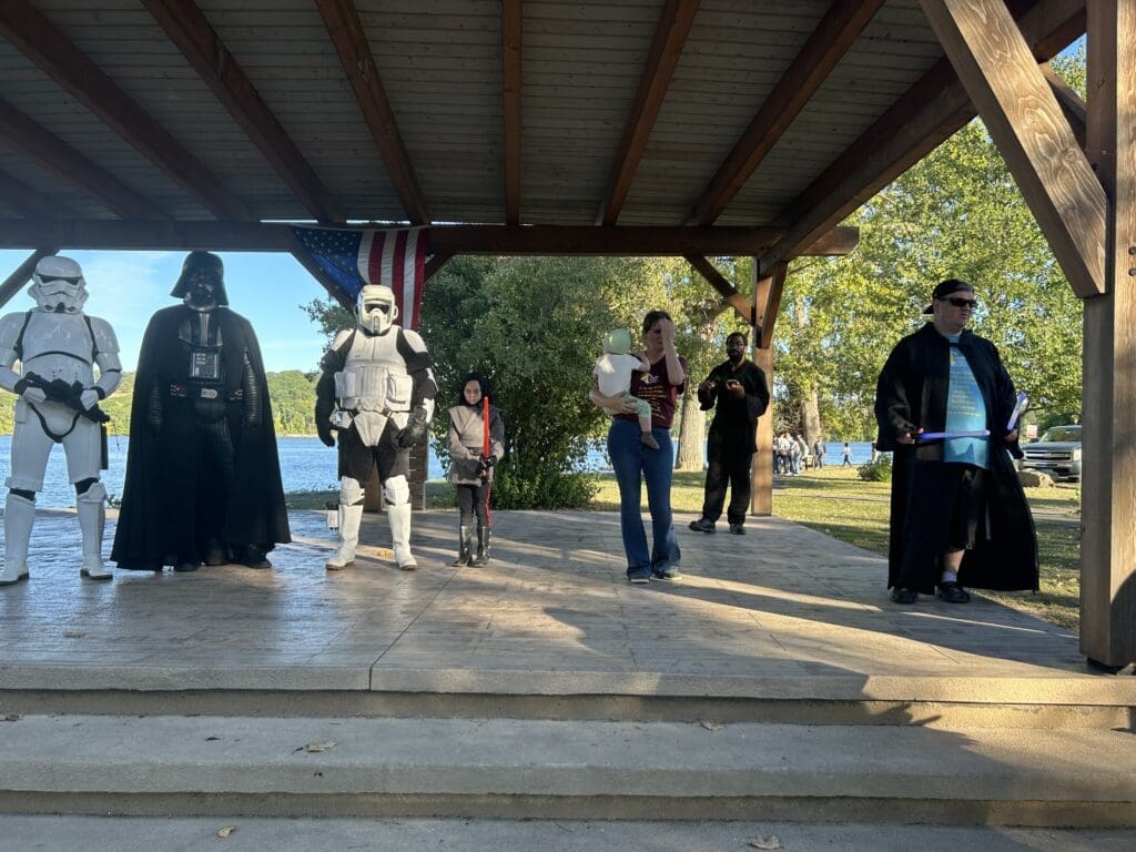 Cosplayers dressed as Star Wars characters standing under a pavilion outdoors.
