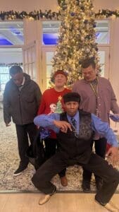 Four people posing in front of tree.