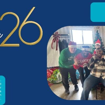 Two people celebrating Christmas indoors, one wearing a green sweater and the other in a plaid shirt.