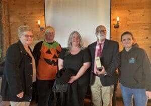 Group of five people posing indoors with festive Halloween attire.