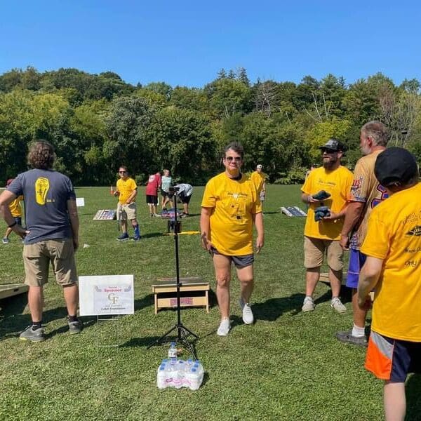 Group of people in yellow shirts playing an outdoor game on a sunny day.